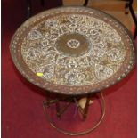 A Moroccan engraved and enamelled decorated brass circular top folding Benares table, dia.58cm