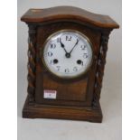 An early 20th century oak cased mantel clock, the enamelled dial showing Arabic numerals, the