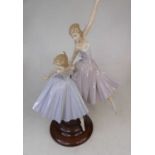 A Lladro porcelain figure group of two ballerinas, upon a polished hardwood plinth, h.49cmIn good