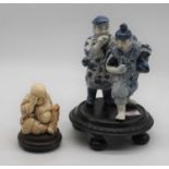 A Chinese blue and white porcelain figure group of two fishermen, upon a carved hardwood stand,