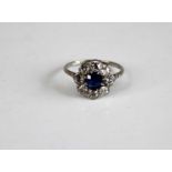 A white metal, sapphire and diamond circular cluster ring, comprising a centre oval sapphire