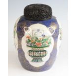 A Chinese famille verte porcelain jar, 19th century, having a profusely carved hardwood lid,