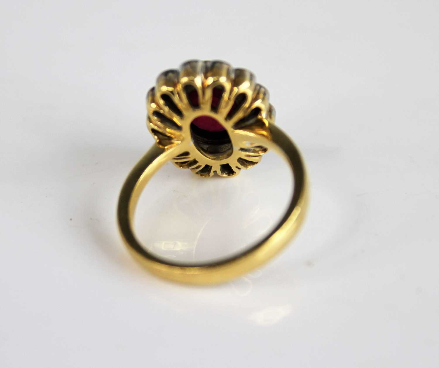 An 18ct yellow and white gold ruby and diamond oval cluster ring, featuring a centre oval facetted - Image 3 of 12