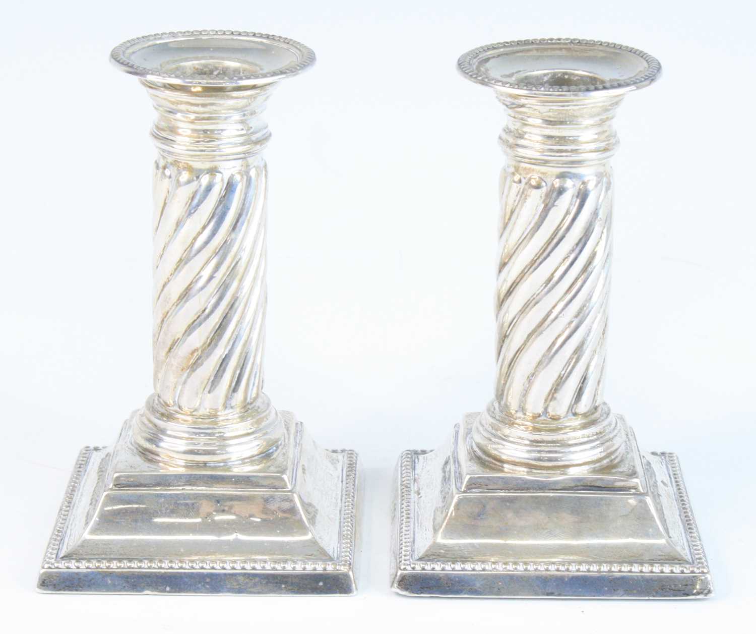 A pair of late Victorian silver squat candlesticks, of twisted Doric column form to loaded stepped