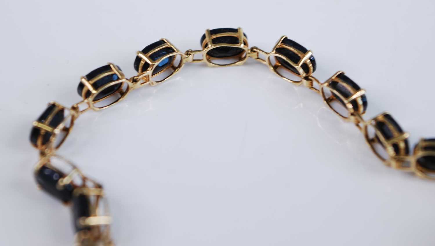 A yellow metal sapphire suite, comprising a sapphire line bracelet featuring 18 oval faceted - Image 6 of 11