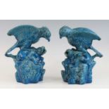 A pair of Chinese blue glazed models of birds of prey, 19th century, each shown attacking a dog upon