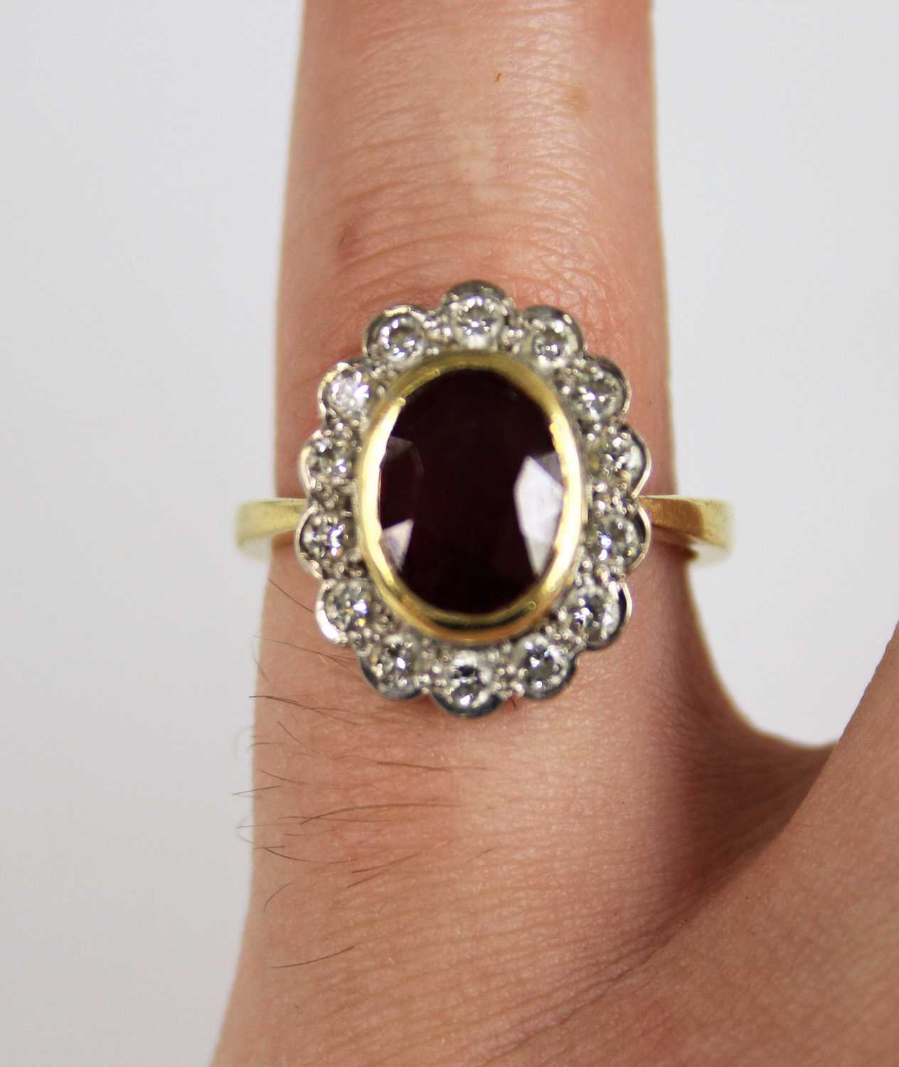 An 18ct yellow and white gold ruby and diamond oval cluster ring, featuring a centre oval facetted - Image 6 of 12