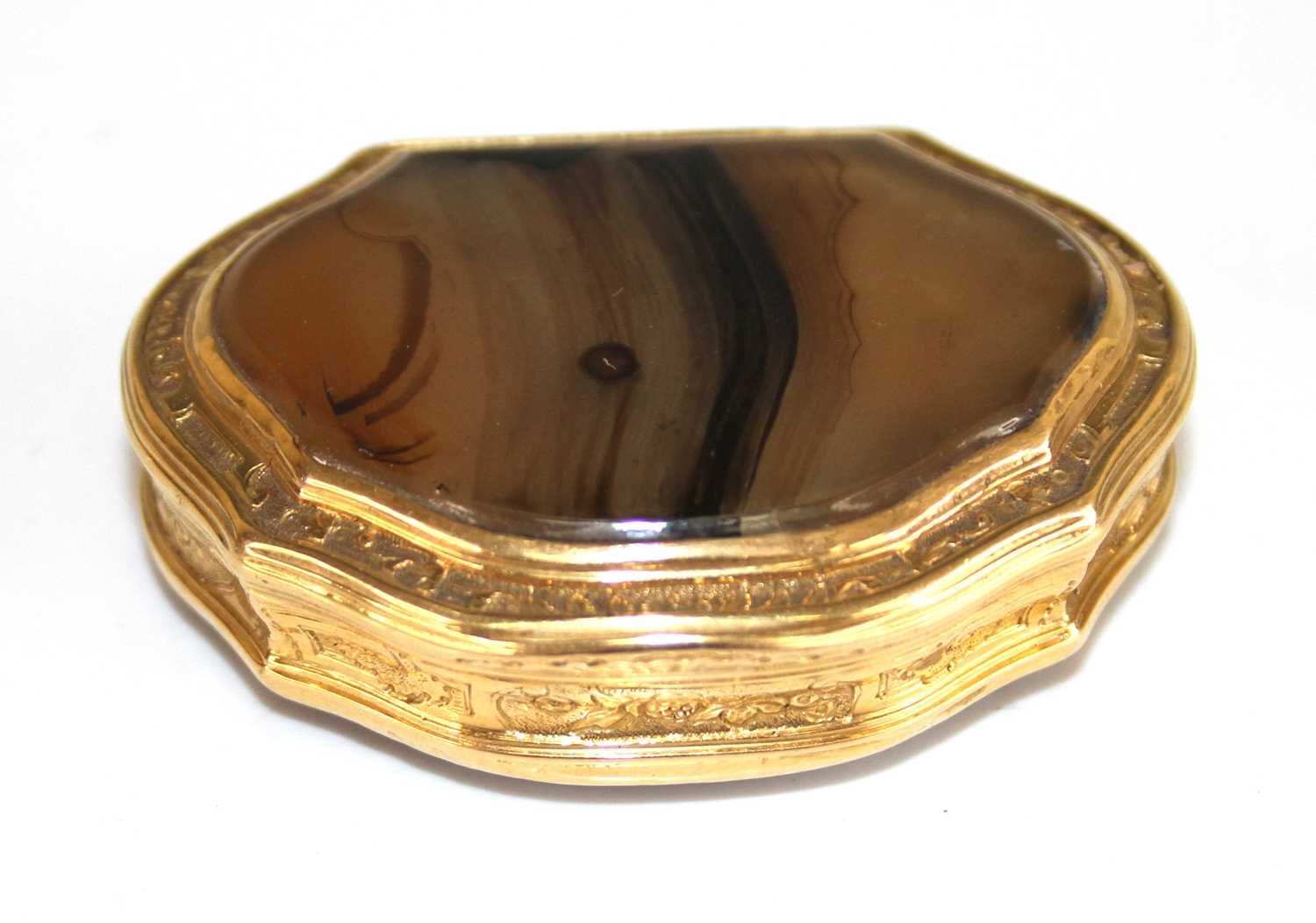 An early 19th century yellow metal and agate snuff box, of shaped oval form, with faceted agate