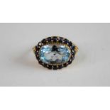 A 9ct yellow gold, blue topaz and sapphire oval cluster ring, featuring a centre oval blue topaz