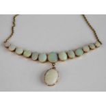 A yellow metal opal necklace, featuring 13 graduated opal cabochons with an opal pendant suspended