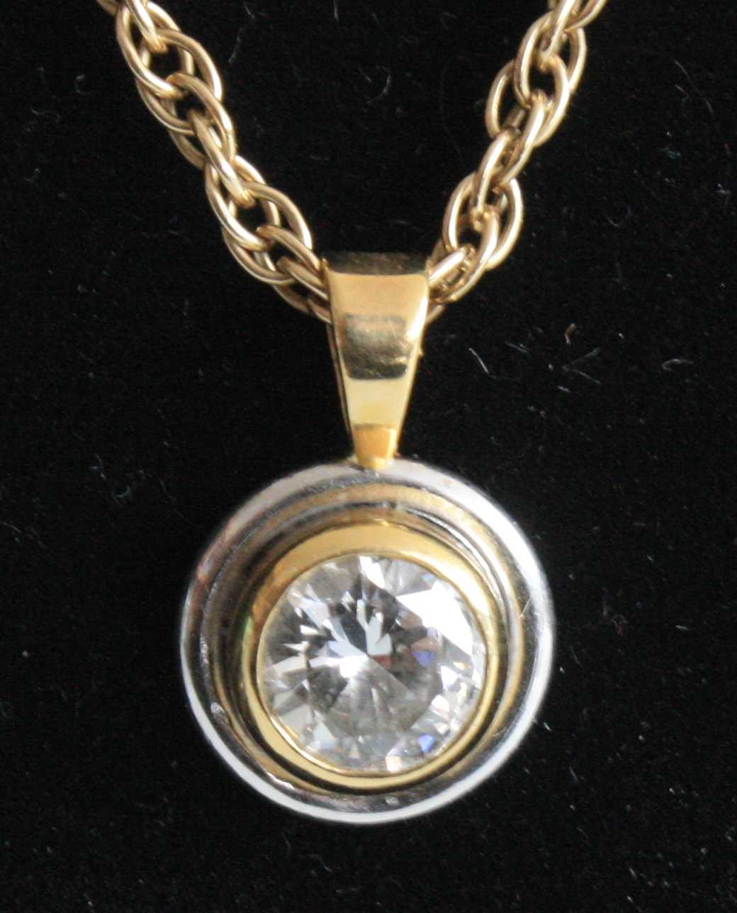 A yellow and white metal diamond single stone pendant, comprising a round brilliant cut diamond in a