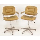 A pair of 1960s British wired chromed metal swivel desk elbow chairs, each with tan leather