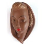 A 1930s Goldscheider painted terracotta wall mask, modelled as a veiled woman, stamped marks and