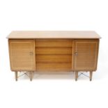 A 1960s Beautility walnut sideboard, having four central drawers flanked by cupboard doors, with