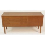 A 1960s Avalon teak compact sideboard, having three long graduated drawers and single fall-front