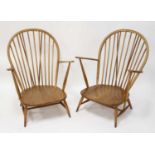 A pair of 1960s Ercol blond elm stickback open armchairs, each having slightly dished panelled seats
