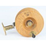 A Revers of France elm 5 1/4" centre pin casting reel, having a single handle and rotating brass