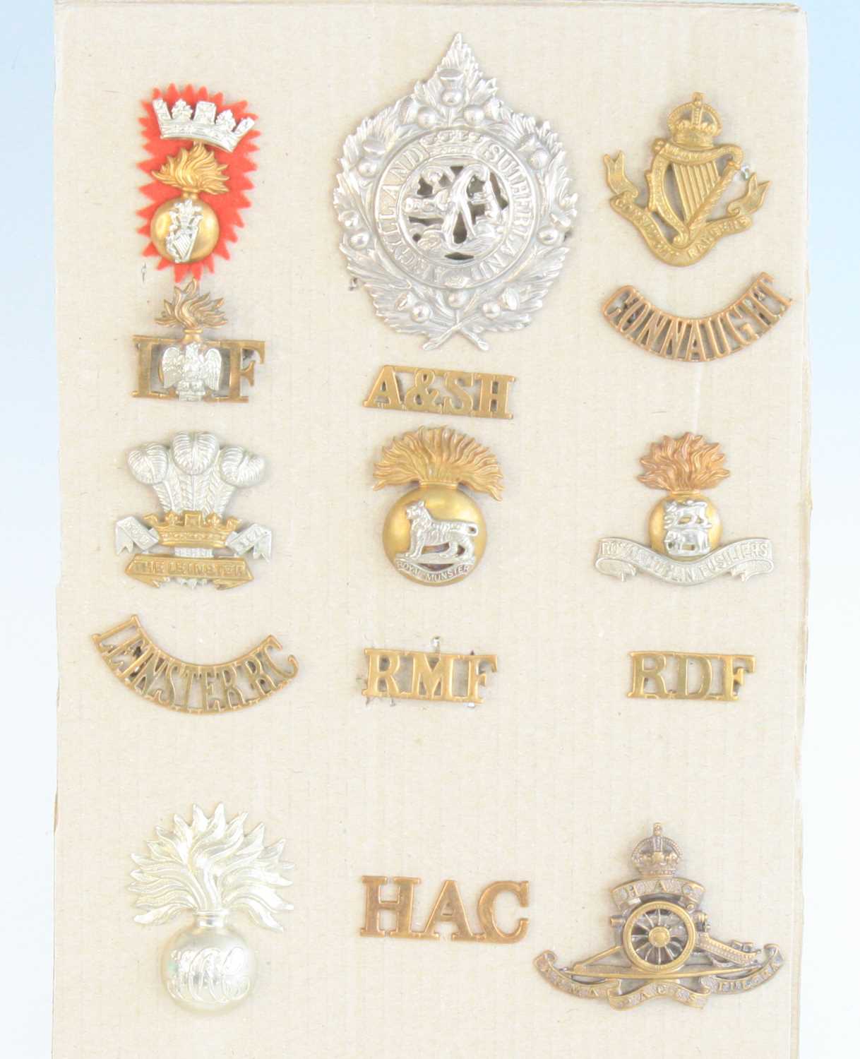 A collection of WW I British Artillery and Infantry cap badges and shoulder titles, to include The