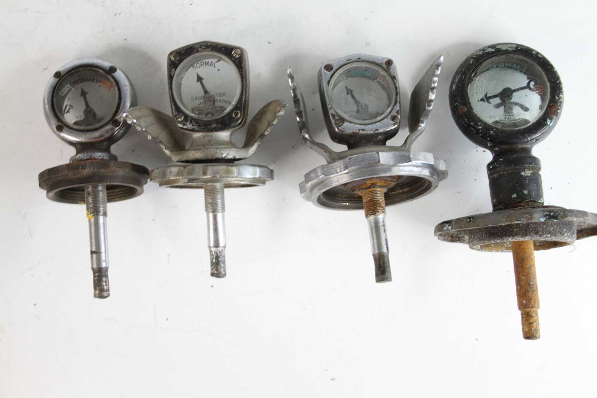 A collection of four various vintage radiator calormeters, two being chromed metal with stylised