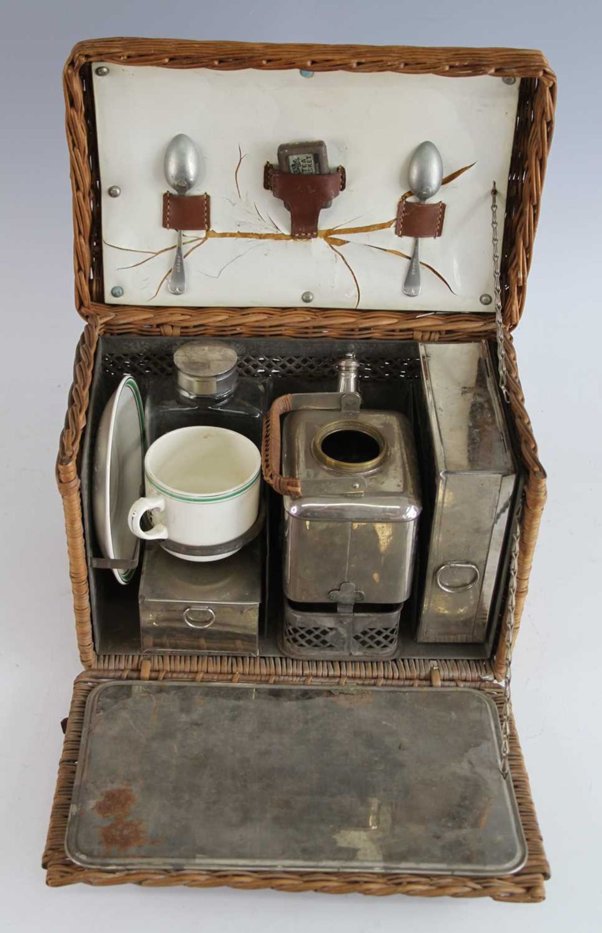 An early 20th century motorists wicker tea basket and contents, to include a spirit kettle, sandwich
