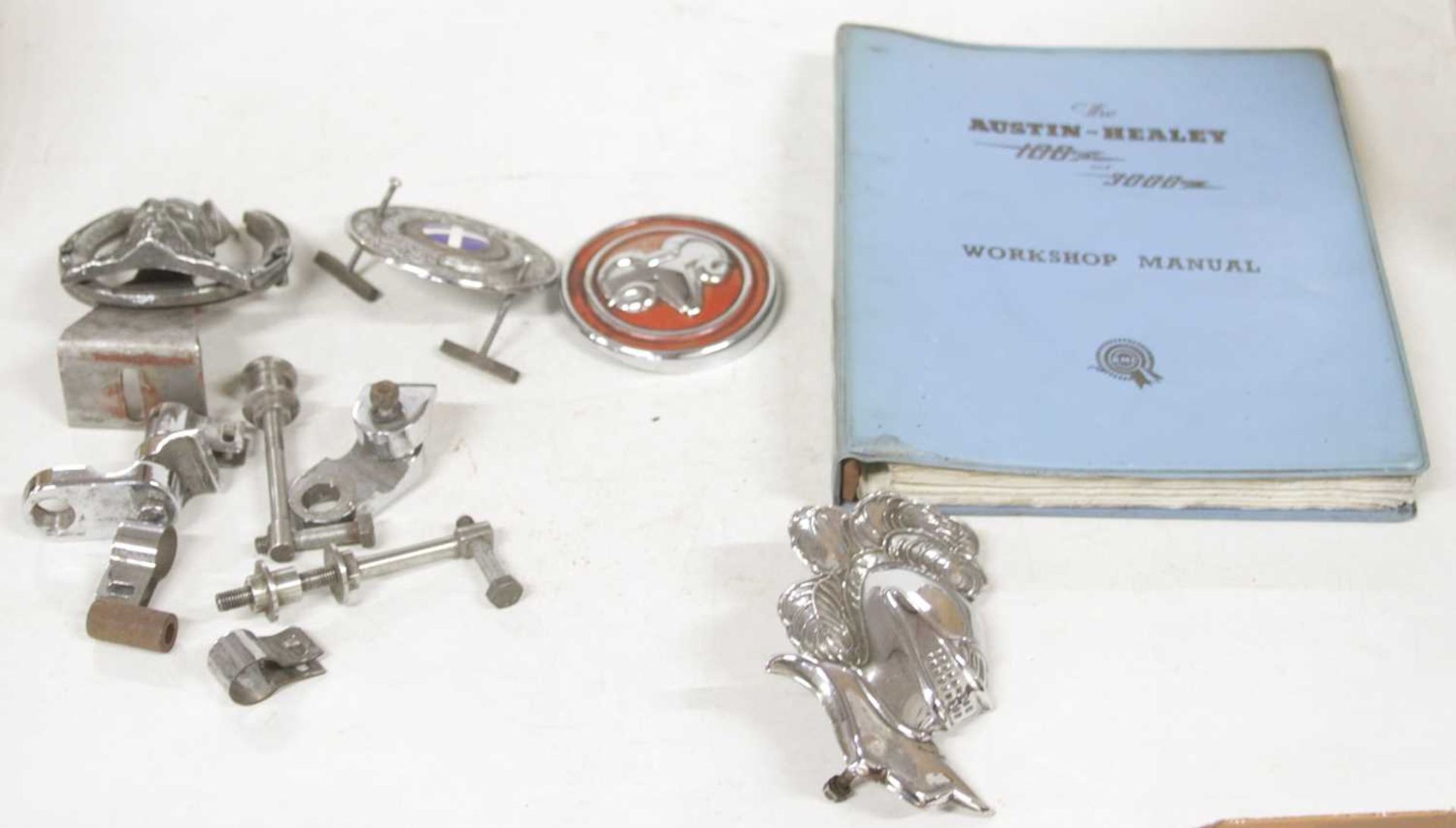 A small number of vintage car badges, to include a visored helmet, Viking, and an Austin Healey