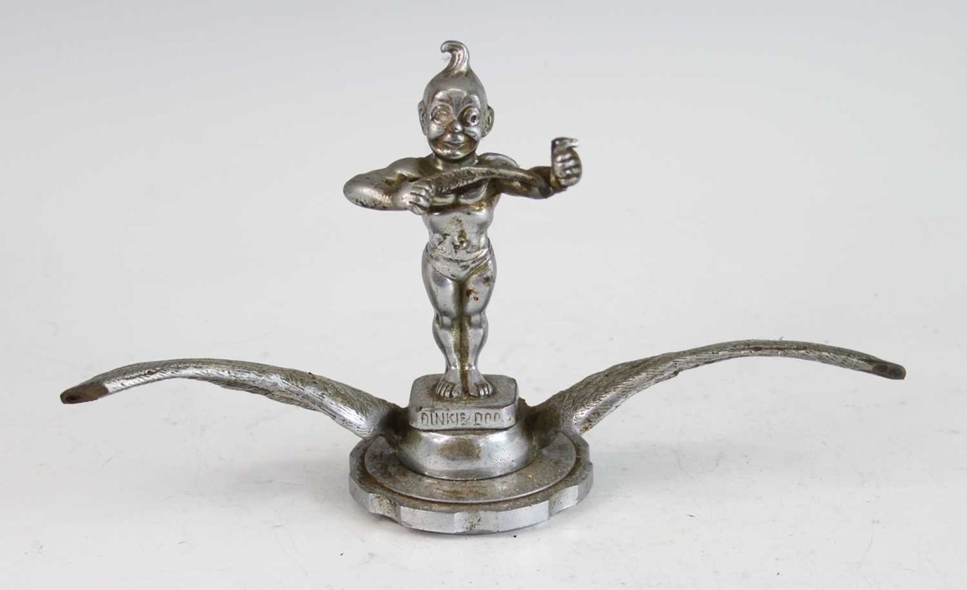 A vintage cast chromed metal car mascot of Dinky Doo, raised on winged and notched circular base,