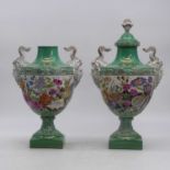 A pair of porcelain urns, each flanked by satin mask handles and decorated with flowers, height