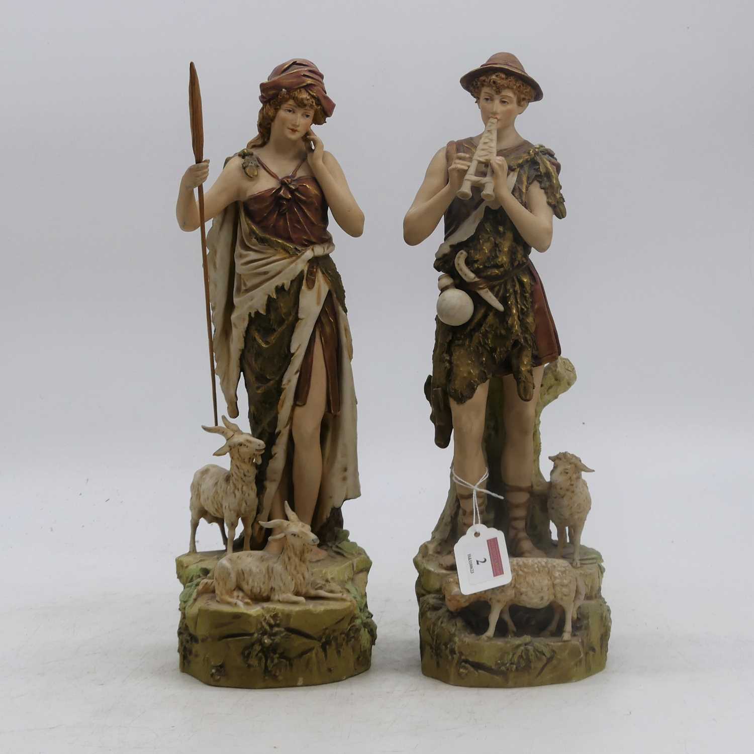 A pair of Royal Dux figures, each shown in standing pose beside sheep and goats, pink triangle