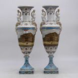 A pair of porcelain vases, each flanked by sphinx handles and decorated with a street scene,