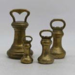A set of four graduated brass weights, numbered 14, 7, 4 and 2, largest height 23cm