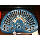 A pierced and cast iron tractor seat titled P.P. Co., painted in blue, red & white, 34 x 42cm