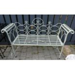 A contemporary pale green painted wrought iron two seater folding garden bench, having scroll arms