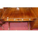 A Regency style mahogany two-drawer drop flap sofa table, raised on outswept supports to brass paw