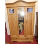 A reclaimed pine three door wardrobe, having central bevelled mirror door enclosing hanging