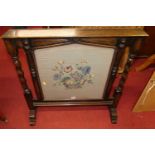 An early 20th century oak and floral needle work inset fire screen having spiral turned and square