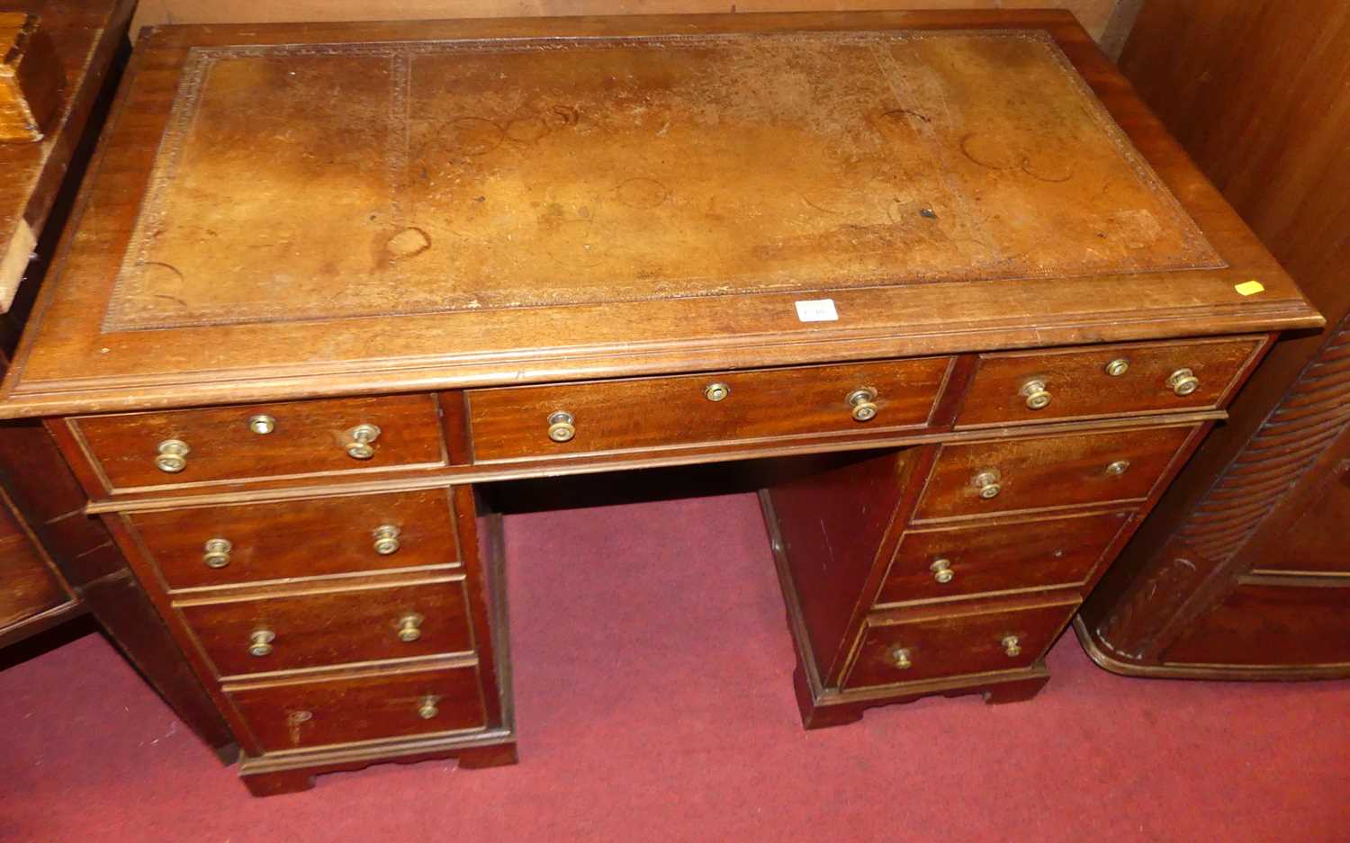 A circa 1900 mahogany and tan leather inset twin pedestal writing desk, having an arrangement of 9