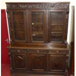 A good circa 1900 heavily carved oak bookcase cupboard, having three glazed upper doors over base