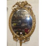 A 19th century git wood and gesso oval bevelled wall mirror, having floral scroll and cornucopia top