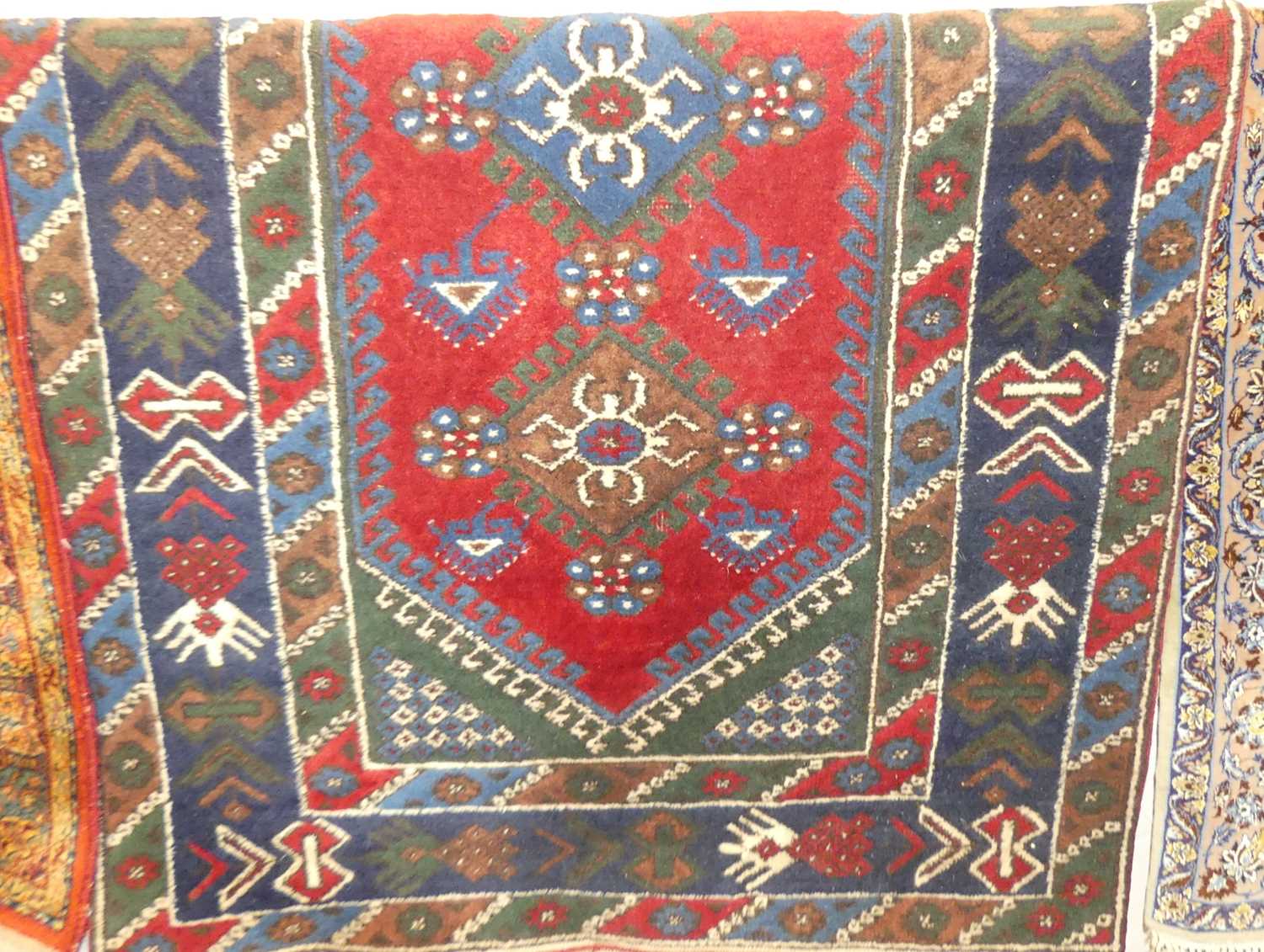 A Turkish woollen red and blue ground rug, the lozenge central field within conforming trailing