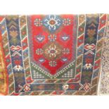 A Turkish woollen red and blue ground rug, the lozenge central field within conforming trailing