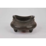 A reproduction Chinese bronze censer, of swollen form and standing upon three feet, bearing two