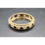 A 9ct gold, blue sapphire and cz set eternity ring, the alternating round cut stones each weighing