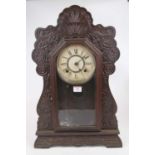 An early 20th century carved and stained walnut American shelf clock, the paper dial showing Roman