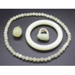 A nephrite plain bangle; together with a beaded necklace, pendant and dress ring (4)