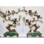 A pair of ornate candelabra in the form of songbirds in a tree, each on a green simulated