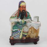 A Chinese porcelain figure of a scholar seated beside a table, on a wooden base, height 23cmSome
