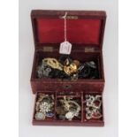 A red leather clad jewellery box and contents to include paste set flower head brooch, enamel brooch