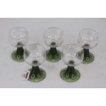 A set of five 20th century coloured glass goblets, the bowls etched with vines, on tapering green