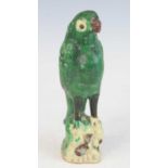 A Chinese green painted pottery parrot, modelled perched on a naturalistic rocky outcrop, heavily