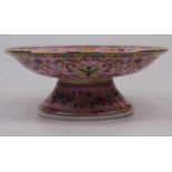 A Chinese porcelain pedestal dish, enamel decorated with crocus flowers on a pink ground, bearing